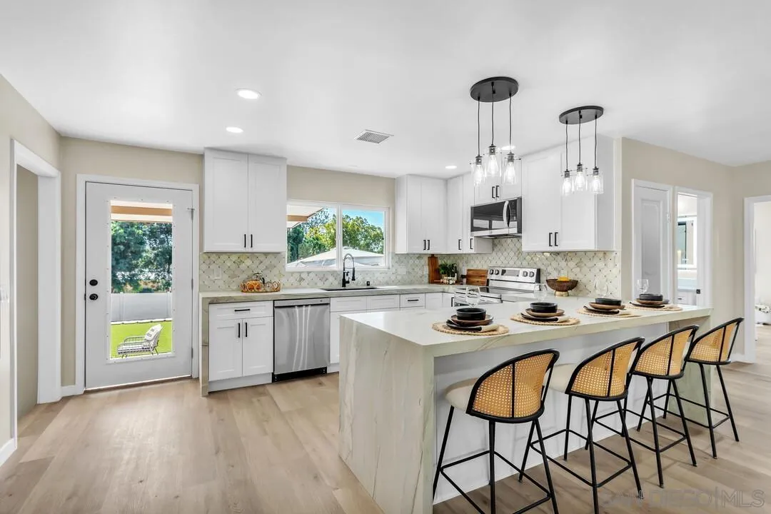 13725 Adrian Street Poway, CA 92064 - Photo 7 of 52 a kitchen with stainless steel appliances granite countertop a stove top oven a sink dishwasher and a refrigerator with wooden floor