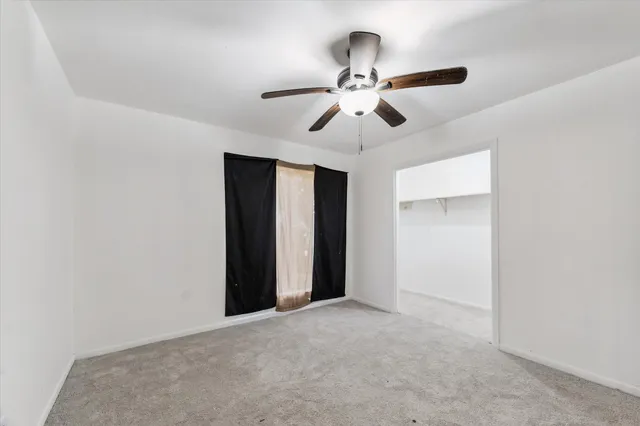 a view of an empty room with a chandelier fan