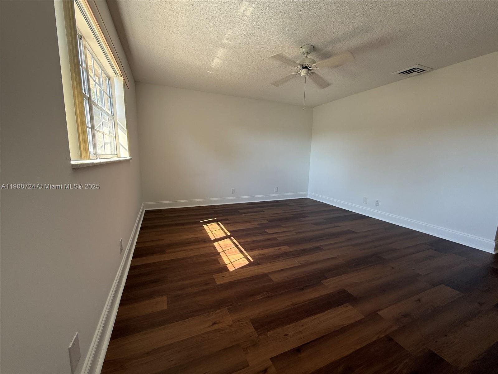8900 West Sample Road, Unit 204 Coral Springs, FL 33065 - Photo 14 of 21 an empty room with wooden floor fan and windows