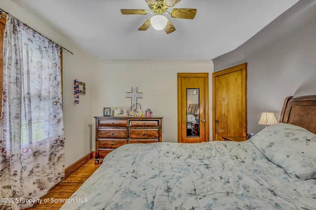 a bedroom with a bed and dresser with wooden floor