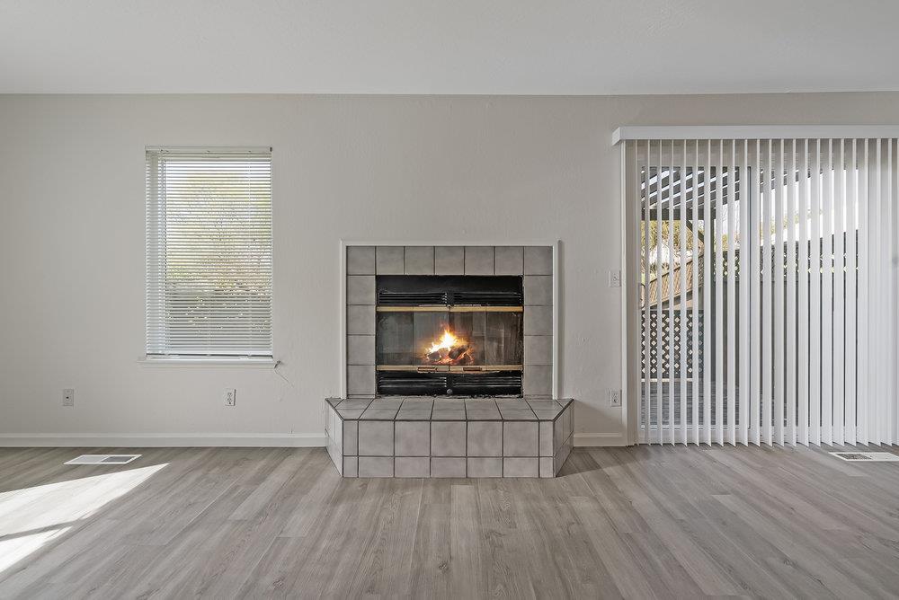 502 Winchester Drive Watsonville, CA 95076 - Photo 13 of 43 an empty room with wooden floor fireplace and windows