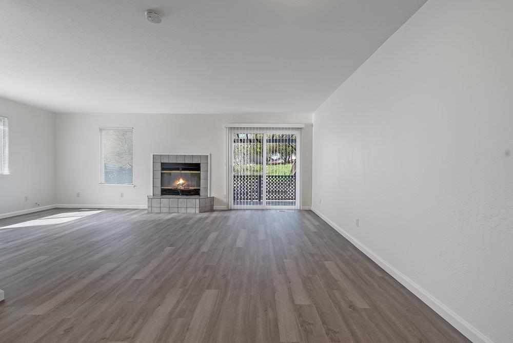 502 Winchester Drive Watsonville, CA 95076 - Photo 10 of 43 an empty room with wooden floor fireplace and windows