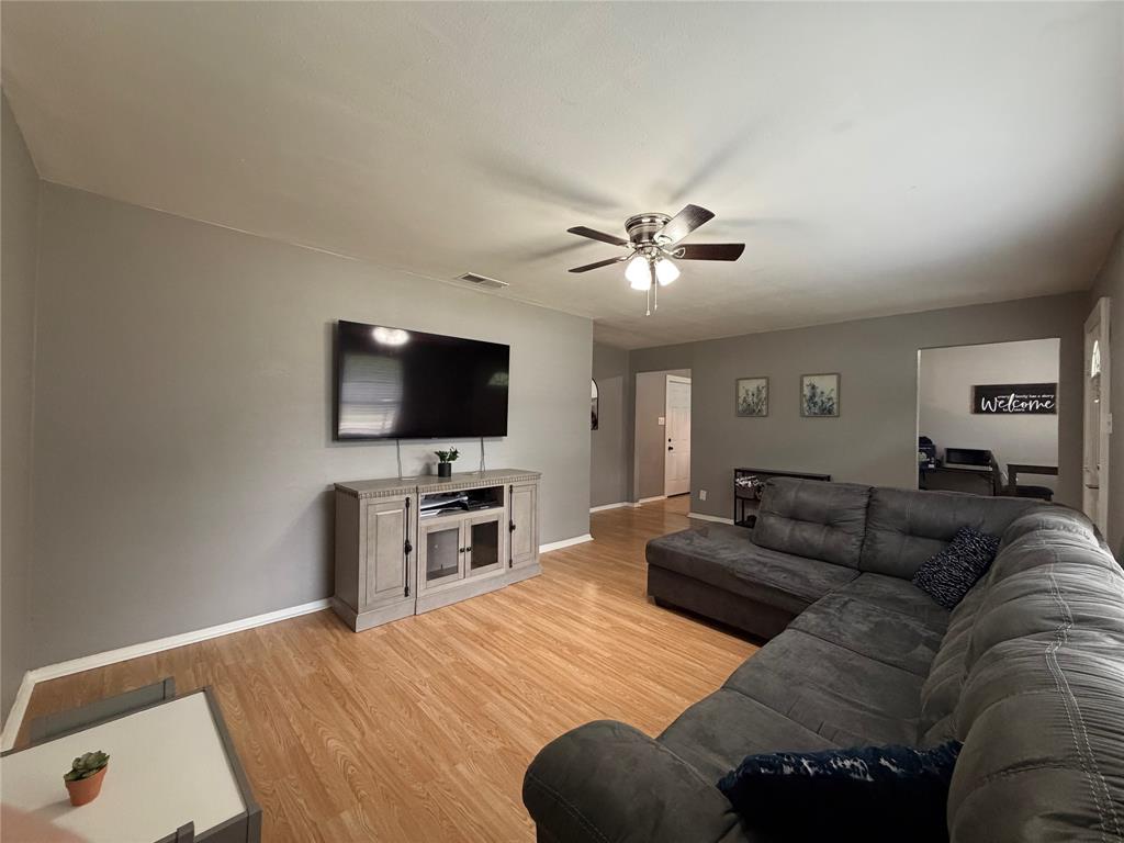 508 Batterson Street Cleburne, TX 76031 - Photo 8 of 28 Open-concept living area featuring wood-finish flooring, a ceiling fan with integrated lighting, and neutral wall tones