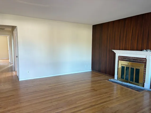 an empty room with wooden floor fireplace and windows
