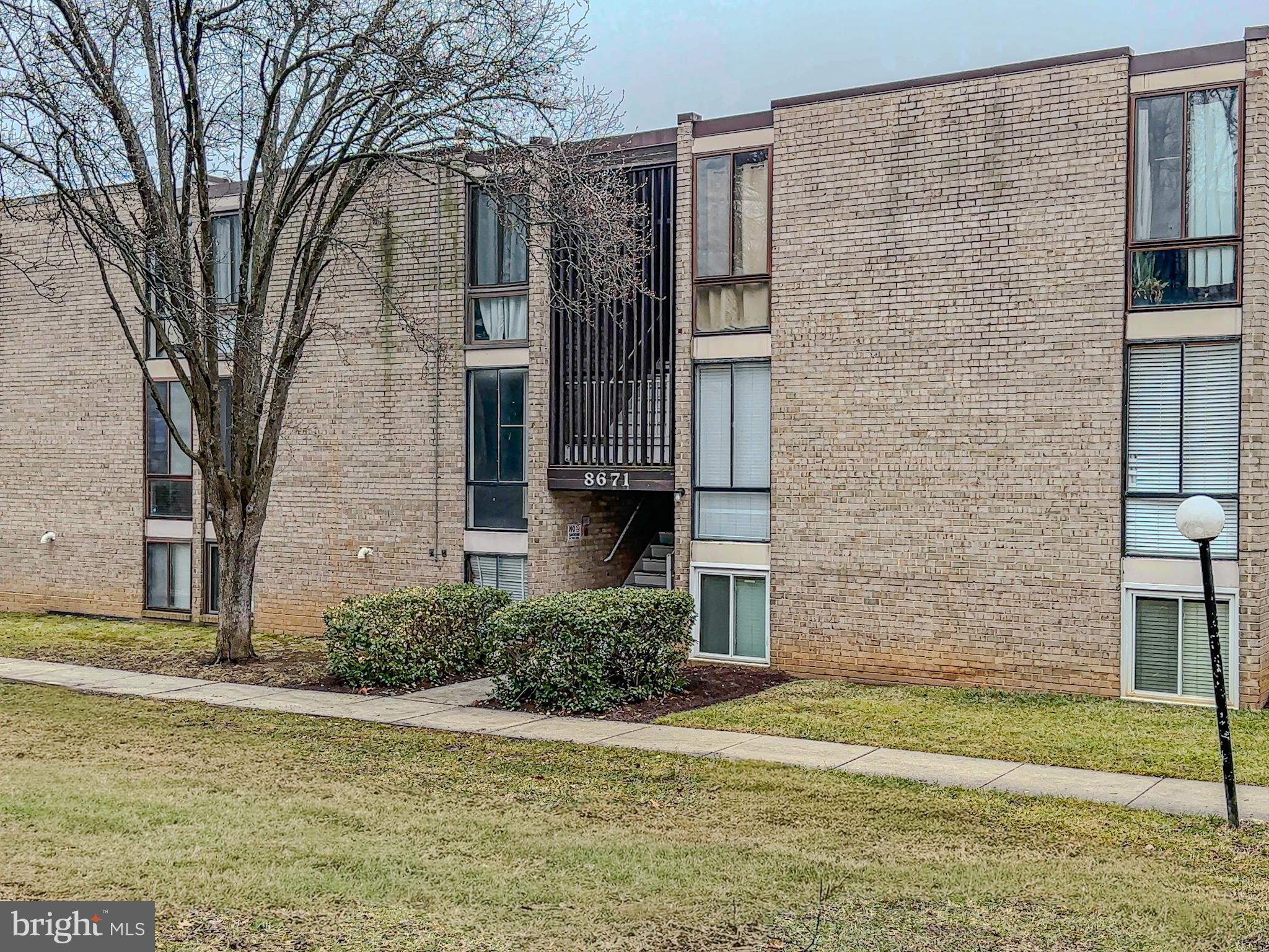 a brick building with a small yard and large trees