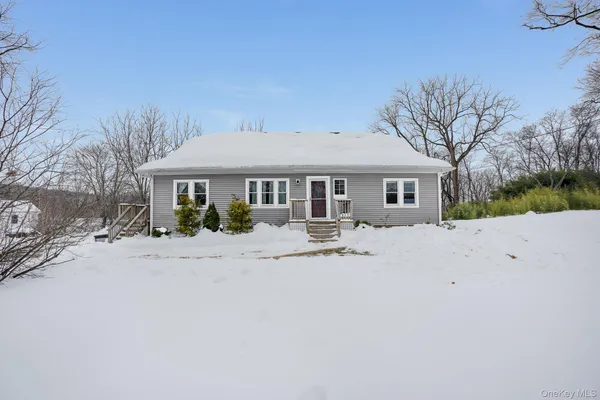 a front view of a house with a dirt yard and a large tree