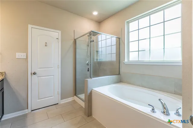 a spacious bathroom with a tub shower and windows