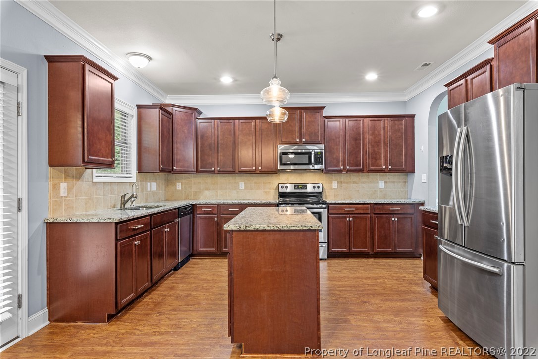 3479 Thrower Road Hope Mills, NC 28348 - Photo 13 of 41 a kitchen with stainless steel appliances granite countertop a refrigerator a sink dishwasher a stove top oven a kitchen island and cabinets with wooden floor