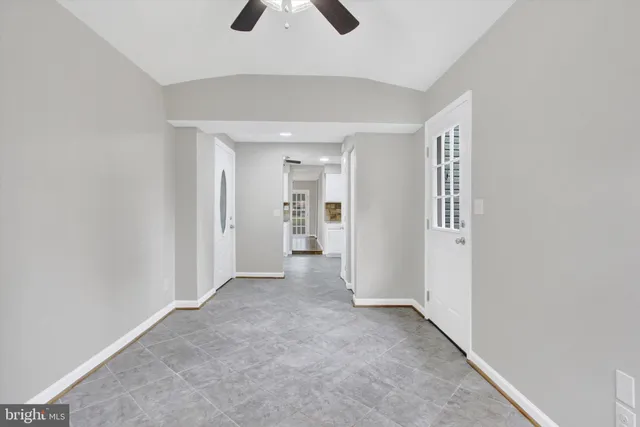 an empty room with ceiling fan and window