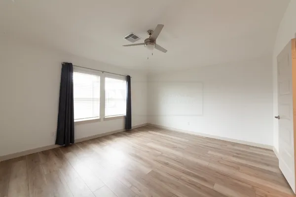 a view of an empty room with a window and wooden floor