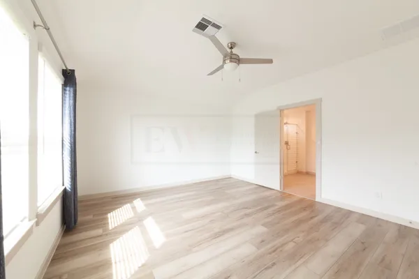 a view of empty room with wooden floor and fan