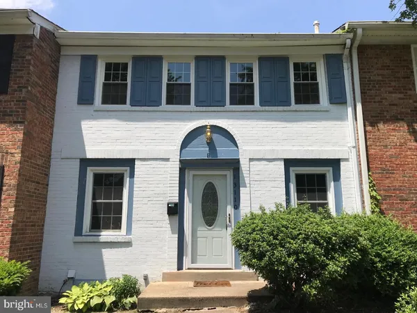 a front view of a house with plants and large tree