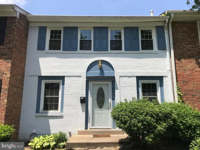 a front view of a house with plants and large tree