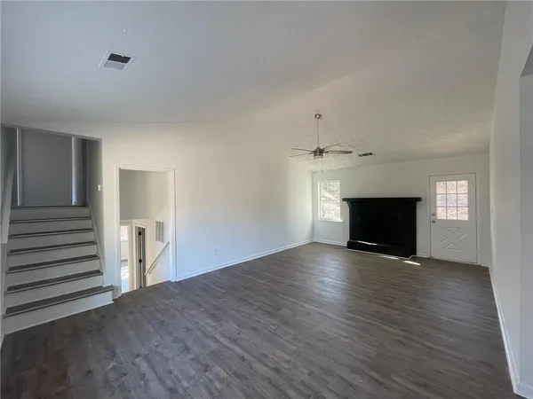 an empty room with wooden floor fireplace and windows