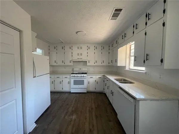 a kitchen with granite countertop lots of white stainless steel appliances cabinets and a sink