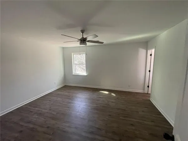 an empty room with wooden floor chandelier fan and windows