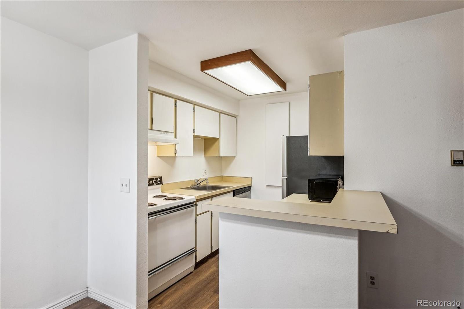 5770 East Warren Avenue, Unit 305 Denver, CO 80222 - Photo 5 of 24 a kitchen with a sink a stove and a refrigerator