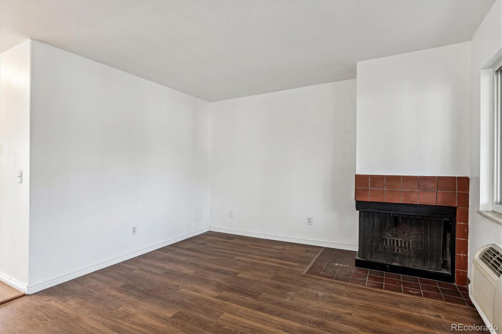 5770 East Warren Avenue, Unit 305 Denver, CO 80222 - Photo 9 of 24 a view of empty room with wooden floor and fireplace
