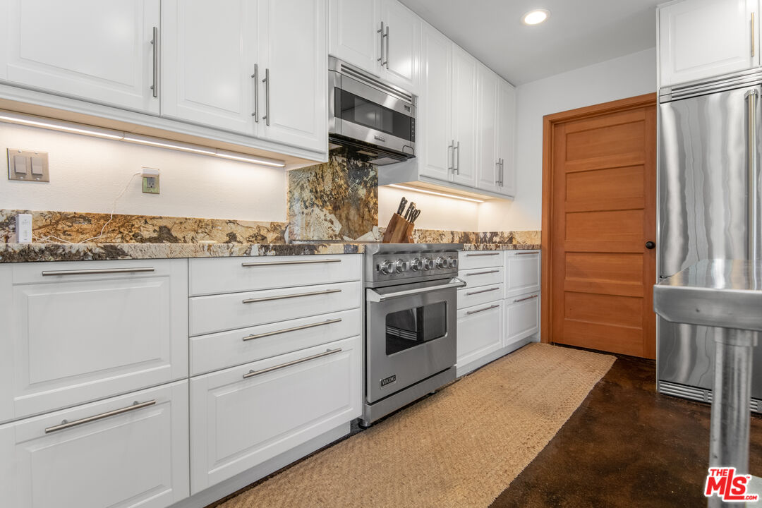 33208 Decker School Road Malibu, CA 90265 - Photo 11 of 51 a kitchen with granite countertop cabinets stainless steel appliances and wooden floor