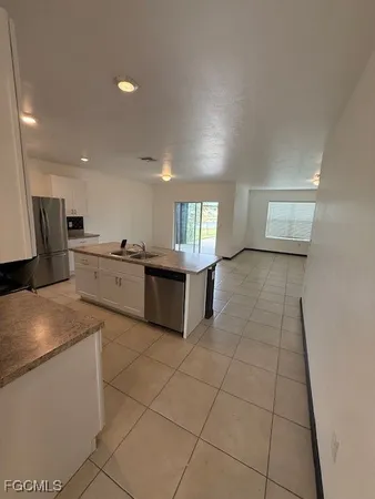a large kitchen with a stove a sink a microwave and cabinets