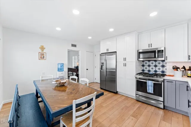 a kitchen with stainless steel appliances granite countertop a stove a refrigerator a oven a sink a table and chairs