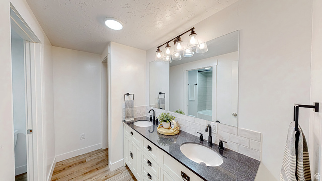 368 East 700 North Springville, UT 84663 - Photo 25 of 55 Full bath with double vanity, light wood-style flooring, tasteful backsplash, a textured ceiling, and a shower