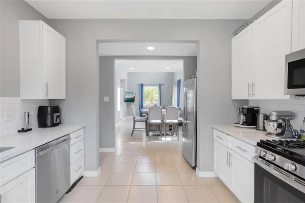 a kitchen with white cabinets and appliances