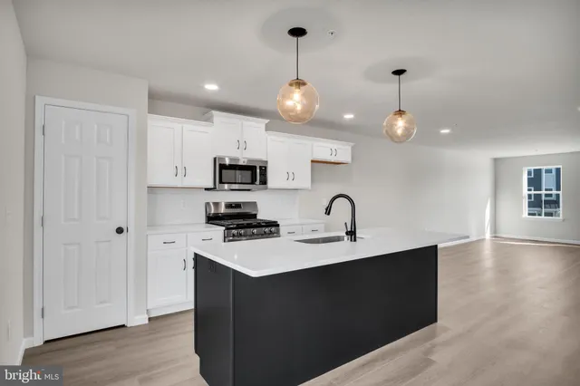 a kitchen with stainless steel appliances a sink a stove a refrigerator cabinets and wooden floor