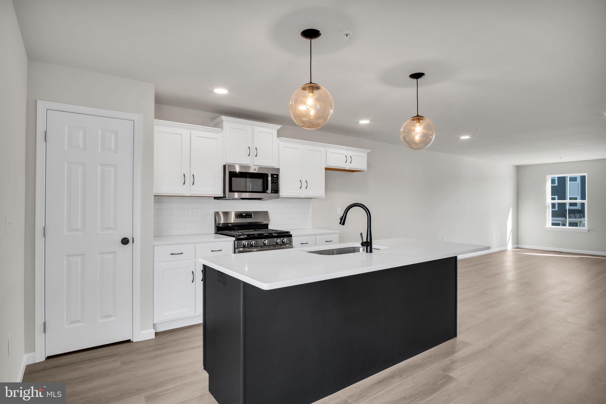 6 Morgan Drive, Unit 1203 Carlisle, PA 17015 - Photo 4 of 13 a kitchen with stainless steel appliances a sink a stove a refrigerator cabinets and wooden floor