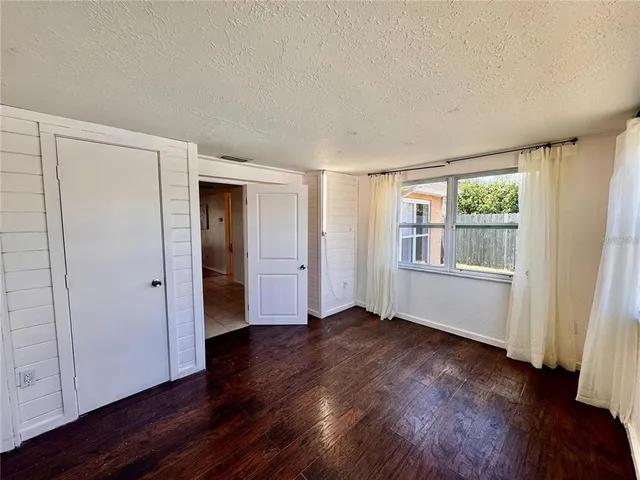 a view of an empty room with wooden floor and window