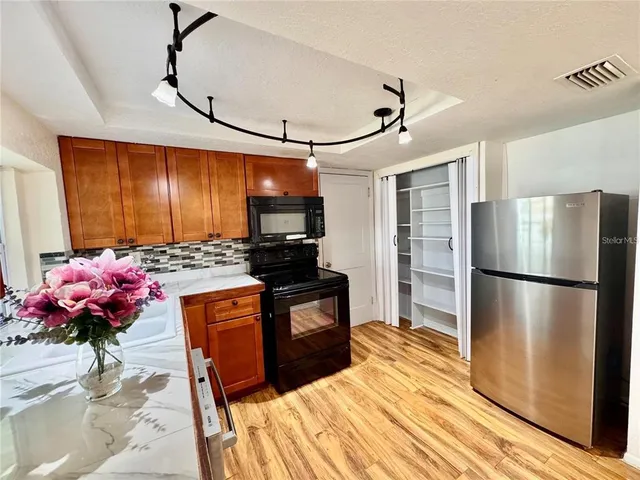 a kitchen with stainless steel appliances granite countertop a refrigerator and a stove top oven