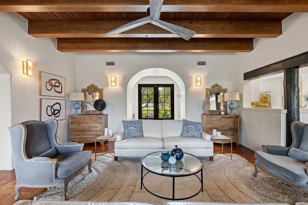 716 North Commons Ford Road Austin, TX 78733 - Photo 7 of 30 Exposed wood ceiling beams accenting a light ceiling, arched doorway with dark framed glass double doors, wall-mounted light fixtures, and terracotta tile flooring