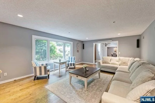 a kitchen with stainless steel appliances granite countertop a refrigerator a sink dishwasher a stove and white countertops with wooden floor