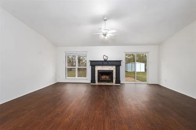 an empty room with wooden floor fireplace and windows