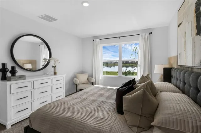 a bedroom with a bed a mirror on dresser and a window