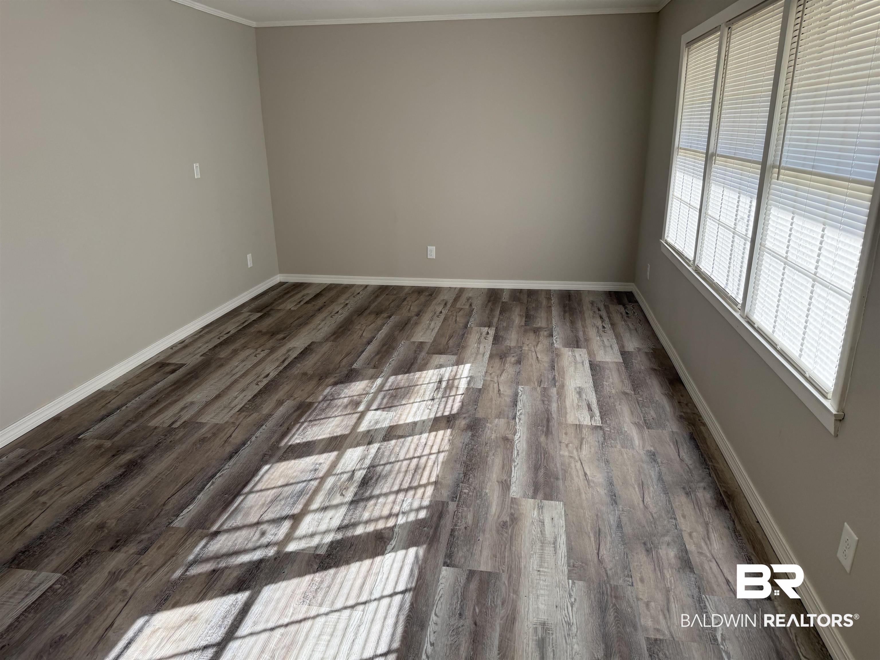 114 Spruce Avenue Brewton, AL 36426 - Photo 3 of 13 Empty room featuring dark wood-type flooring and crown molding