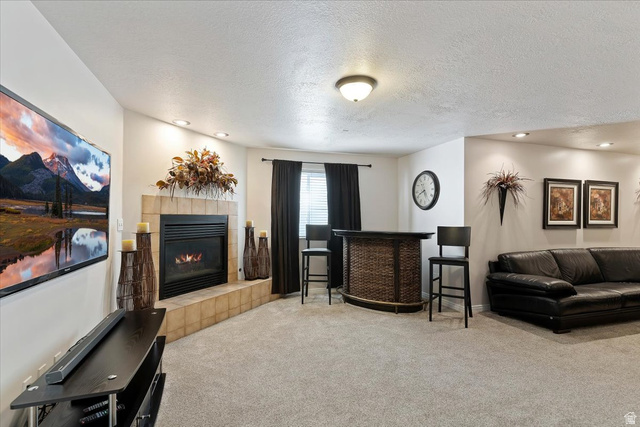 1924 North 2000th Street East Layton, UT 84040 - Photo 29 of 41 Living room with light colored carpet, a textured ceiling, a fireplace, and recessed lighting
