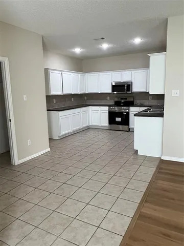 a kitchen with stainless steel appliances kitchen island granite countertop a refrigerator and cabinets