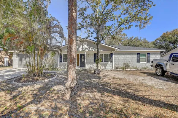 a view of a white house next to a road and large trees