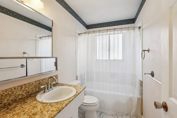 a bathroom with a granite countertop sink toilet and shower