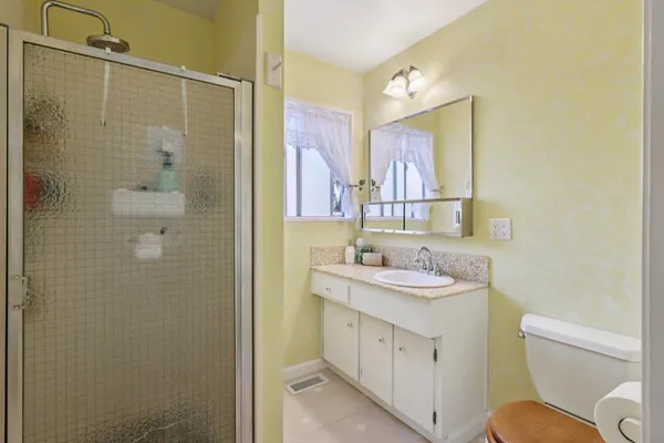 a bathroom with a granite countertop sink toilet a mirror a vanity and shower