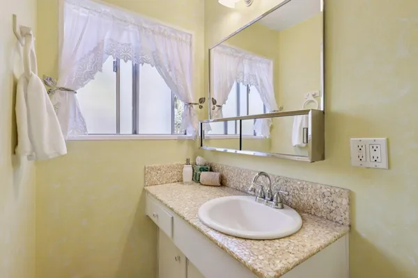 a bathroom with a granite countertop sink and a mirror
