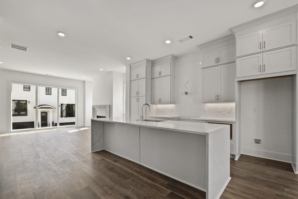 a large white kitchen with center island and stainless steel appliances