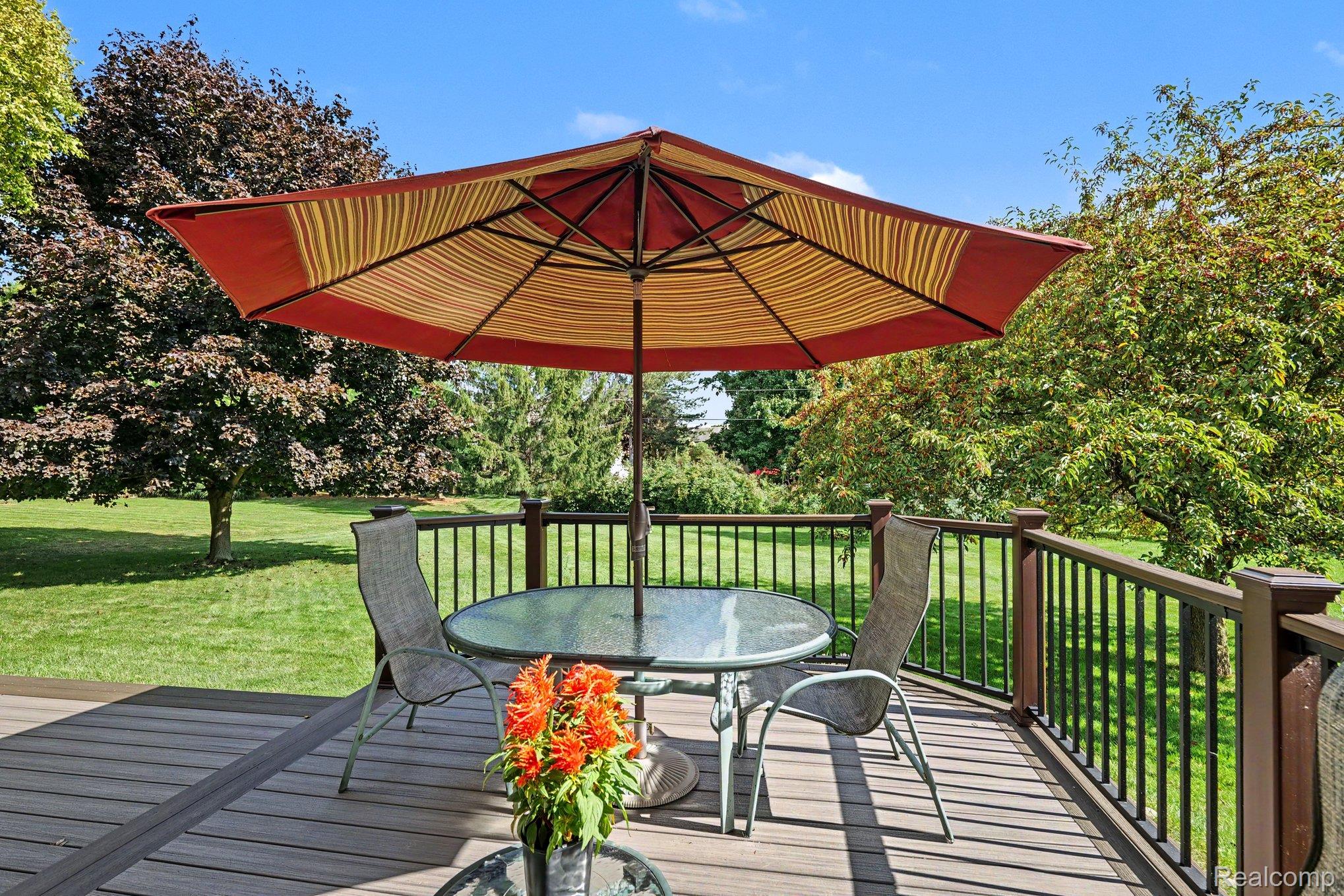 1692 Ridgecrest Rochester, MI 48306 - Photo 23 of 31 Expansive backyard featuring a manicured lawn, mature trees, and a spacious wood-finish deck with a dark railing