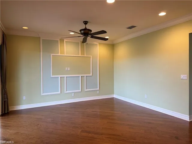 an empty room with wooden floor ceiling fan and window
