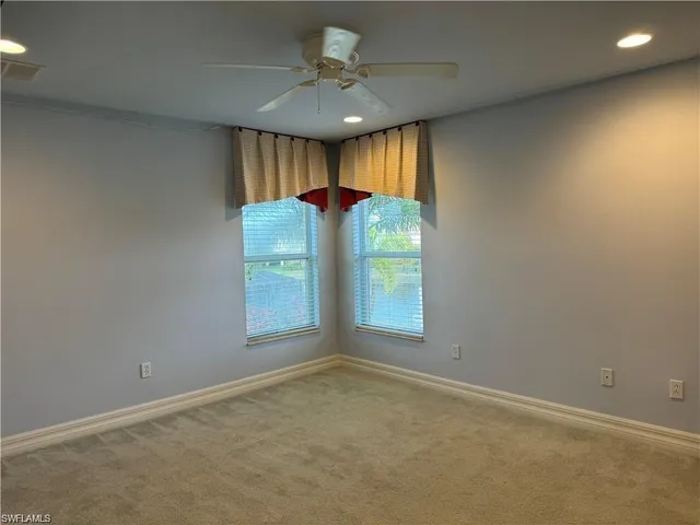 an empty room with a window and a ceiling fan