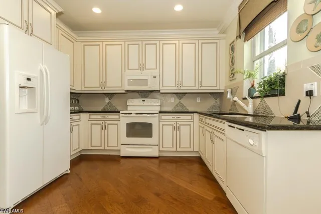a kitchen with granite countertop white cabinets and white appliances