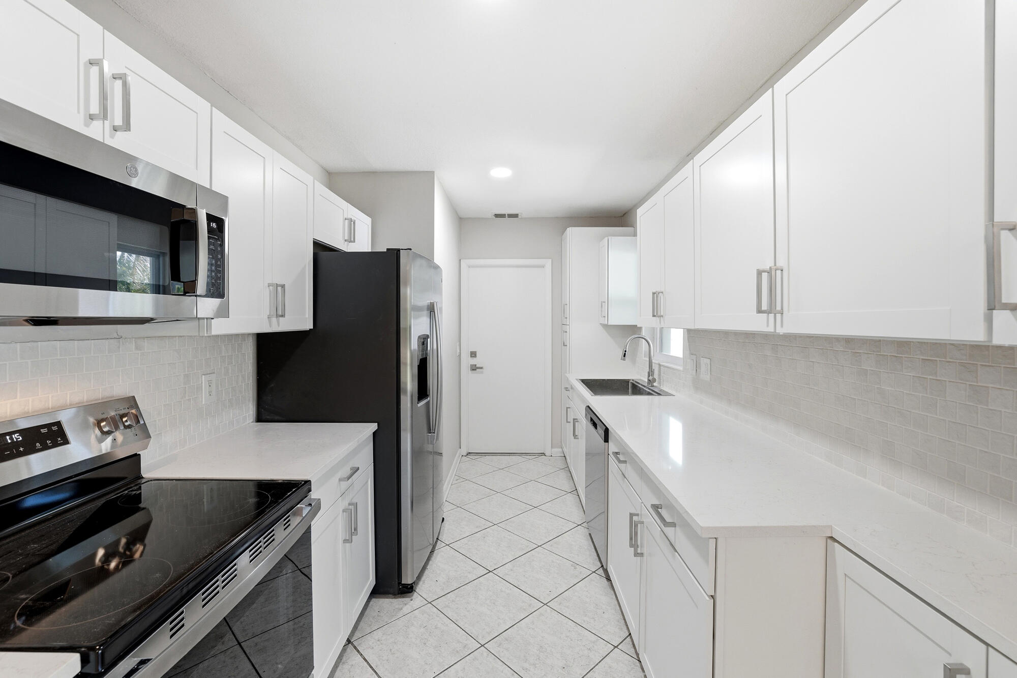 301 Wilma Circle Riviera Beach, FL 33404 - Photo 8 of 35 a kitchen with stainless steel appliances a sink stove and refrigerator