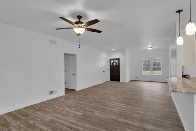 a view of an empty room with a window and wooden floor