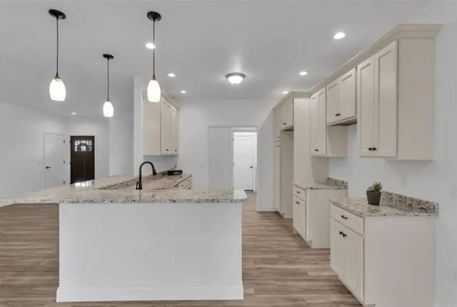 a large kitchen with kitchen island a stove a sink a center island and wooden floor